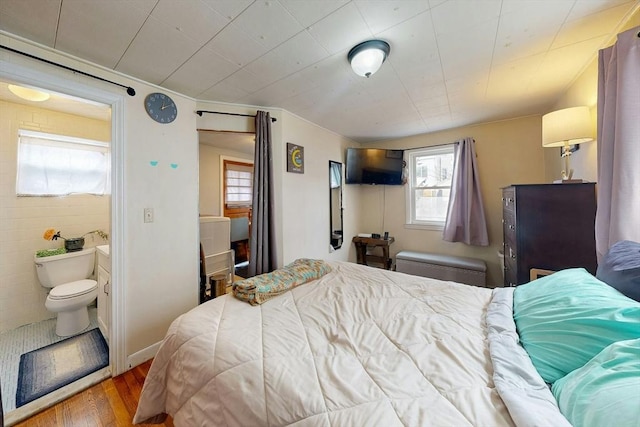 bedroom featuring connected bathroom and wood finished floors