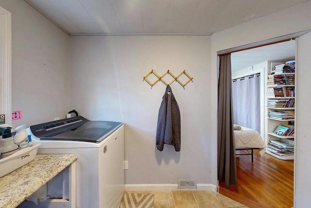 laundry area with washer and clothes dryer, visible vents, wood finished floors, laundry area, and baseboards