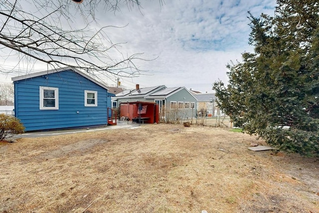 rear view of property featuring an outbuilding and fence