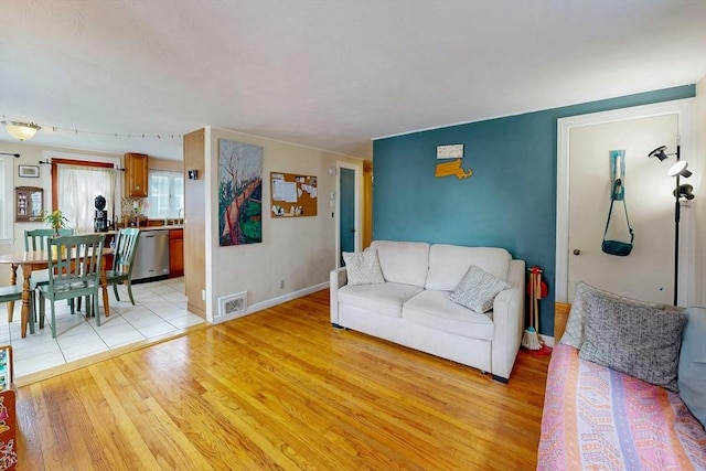 living room featuring light wood-type flooring, baseboards, and visible vents