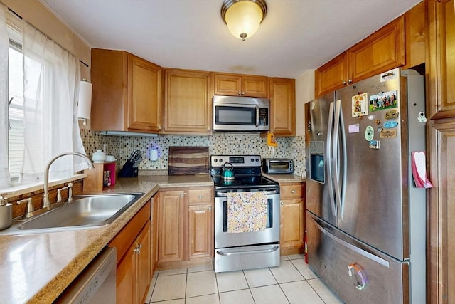 kitchen with stainless steel appliances, a sink, decorative backsplash, and light tile patterned floors