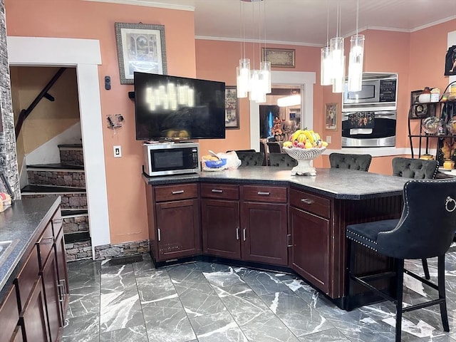 kitchen featuring pendant lighting, stainless steel appliances, a notable chandelier, ornamental molding, and a kitchen bar