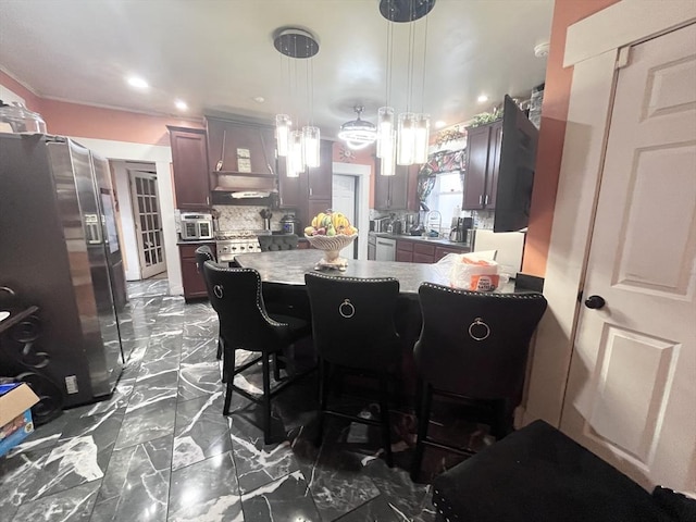 kitchen with decorative light fixtures, a breakfast bar area, decorative backsplash, stainless steel refrigerator with ice dispenser, and custom range hood