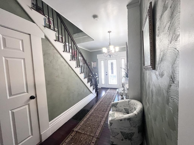 foyer featuring crown molding, dark wood-type flooring, and a chandelier