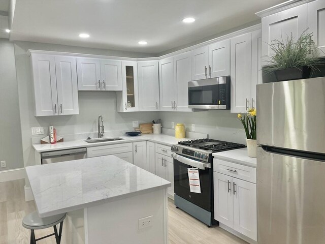 43 Aubin St Unit 1, Amesbury, MA 01913 - kitchen featuring stainless steel appliances, a sink, a center island, light wood-type flooring, and white cabinetry