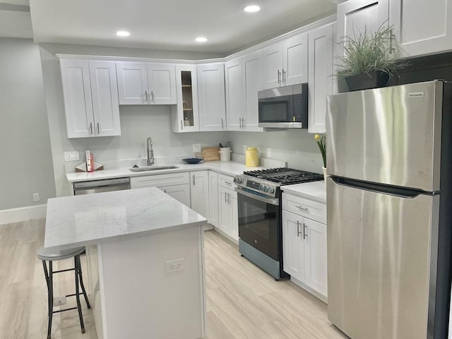 43 Aubin St Unit 1, Amesbury, MA 01913 - kitchen with stainless steel appliances, a sink, light wood-type flooring, a center island, and white cabinets
