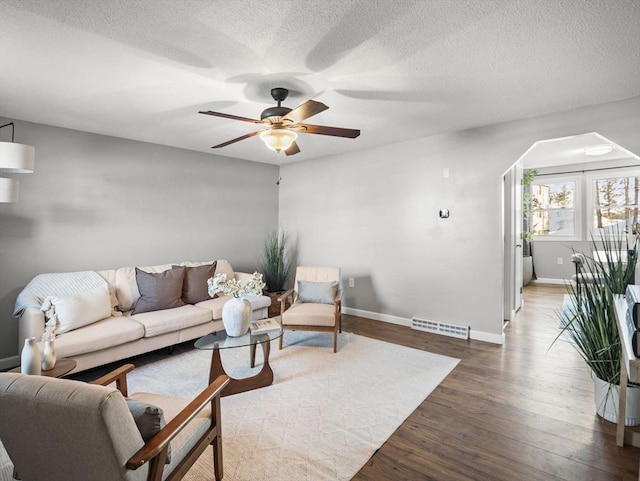 living area featuring dark wood-style floors, a textured ceiling, visible vents, and baseboards