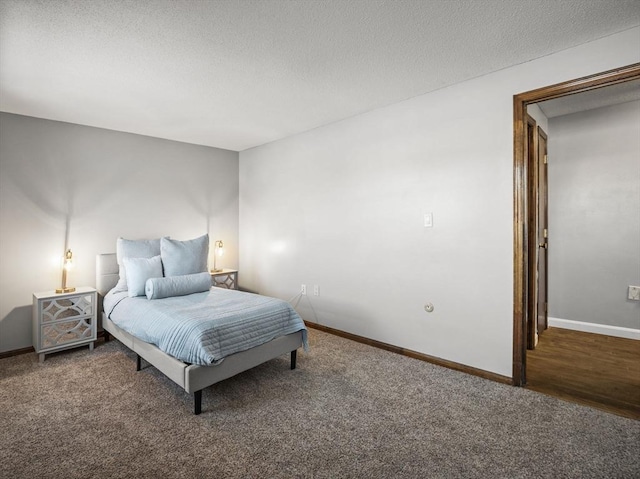 bedroom featuring a textured ceiling, dark carpet, and baseboards