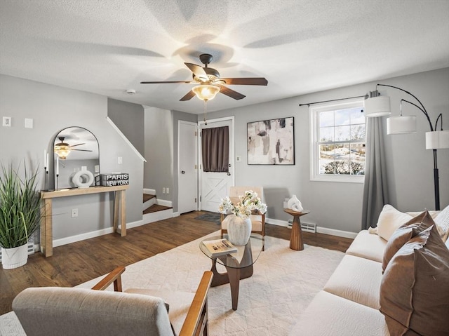 living area with baseboards, visible vents, stairway, wood finished floors, and a textured ceiling