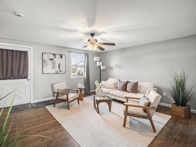 living area featuring a textured ceiling, ceiling fan, wood finished floors, and baseboards