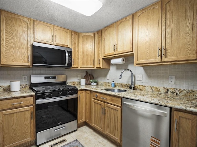 kitchen with light tile patterned floors, a sink, visible vents, appliances with stainless steel finishes, and light stone countertops