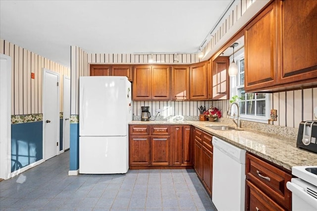 kitchen featuring light stone countertops, pendant lighting, white appliances, and sink