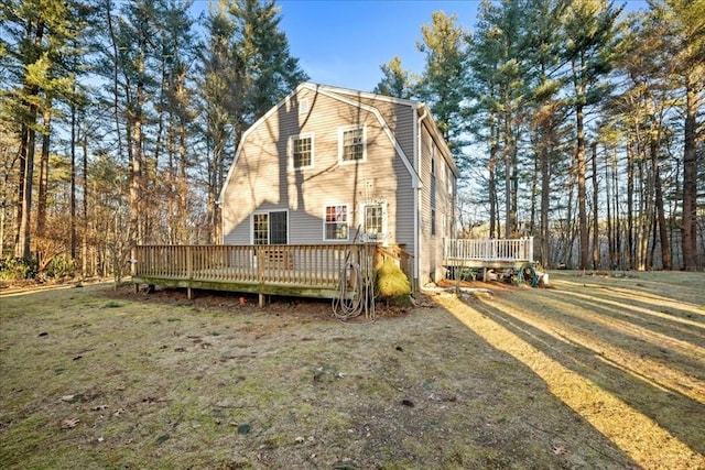 rear view of property featuring a wooden deck and a yard