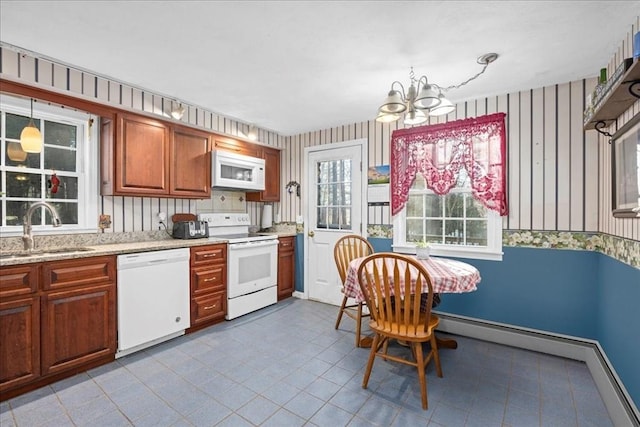 kitchen featuring white appliances, an inviting chandelier, sink, decorative light fixtures, and light stone counters