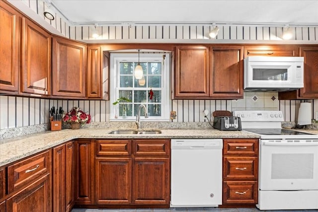 kitchen featuring white appliances, tasteful backsplash, light stone counters, and sink