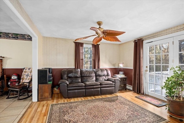 living room with hardwood / wood-style floors, ceiling fan, a healthy amount of sunlight, and a baseboard heating unit