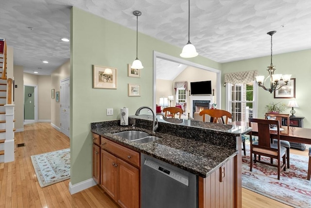 89 Cortland Dr Unit 89, North Andover, MA 01845 - kitchen with stainless steel dishwasher, a sink, a lit fireplace, light wood-style flooring, and baseboards