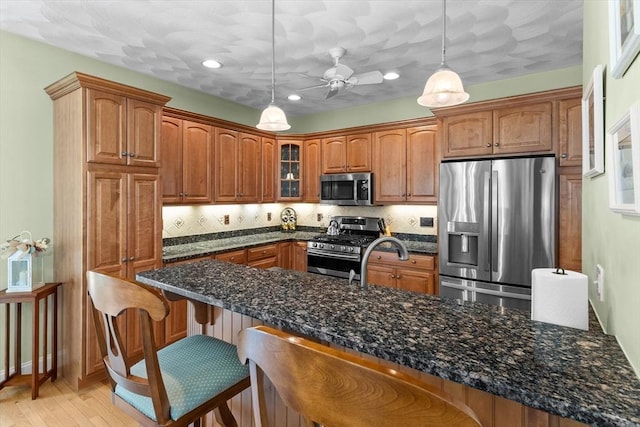 89 Cortland Dr Unit 89, North Andover, MA 01845 - kitchen featuring stainless steel appliances, a kitchen breakfast bar, glass insert cabinets, brown cabinetry, and recessed lighting