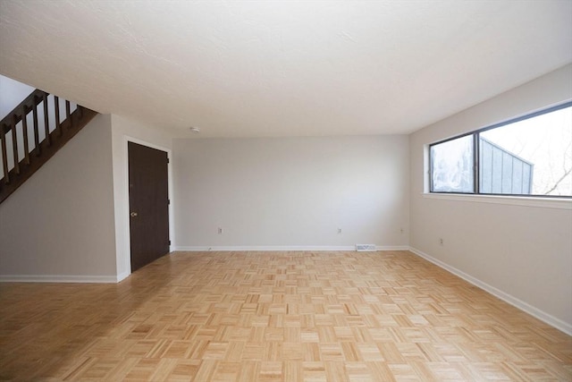 unfurnished room featuring stairs, visible vents, and baseboards