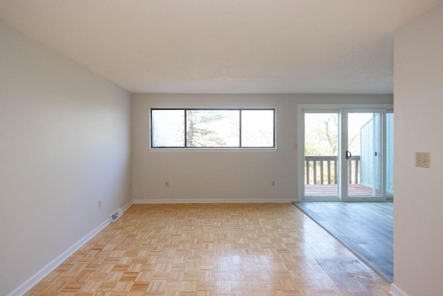 unfurnished room with plenty of natural light, baseboards, and visible vents