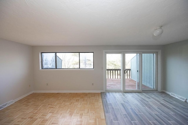 unfurnished room featuring visible vents, baseboards, light wood-style floors, and a textured ceiling