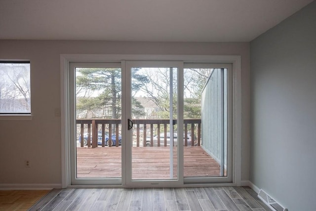 doorway featuring visible vents, plenty of natural light, baseboards, and wood finished floors