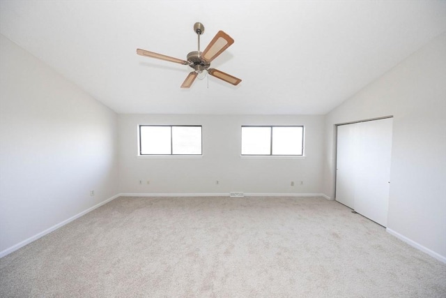 unfurnished room with vaulted ceiling, light colored carpet, baseboards, and ceiling fan