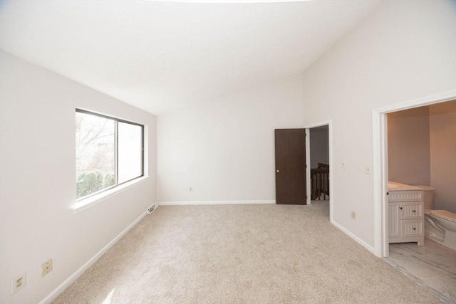 unfurnished bedroom featuring lofted ceiling, baseboards, and light carpet