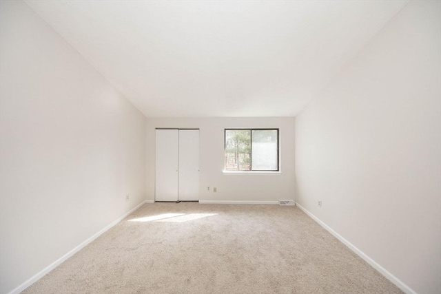 unfurnished bedroom with light carpet, visible vents, a closet, and baseboards