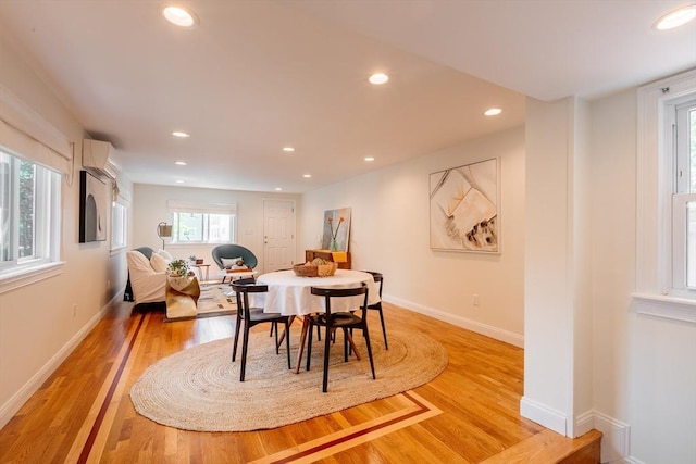 dining area featuring healthy amount of natural light, light wood-type flooring, recessed lighting, an AC wall unit, and baseboards