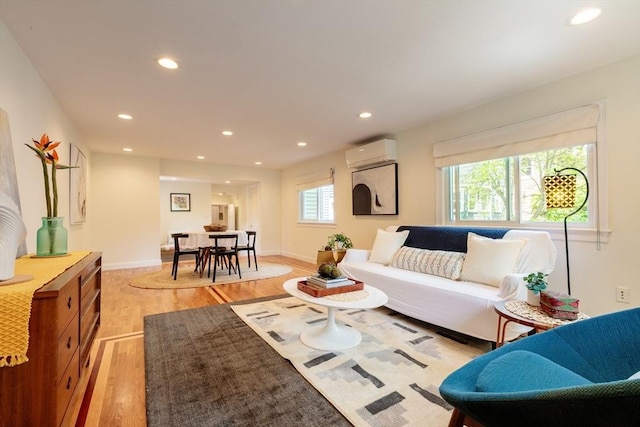 living area with a wall mounted air conditioner, light wood-style flooring, recessed lighting, and baseboards