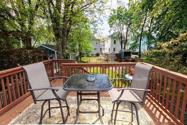 wooden deck with outdoor dining space, fence, a storage unit, and an outdoor structure