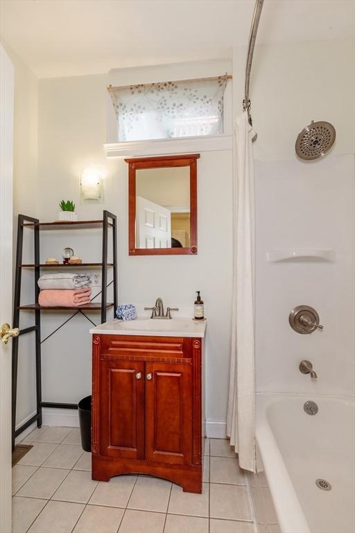 bathroom with tile patterned flooring, shower / bathtub combination with curtain, vanity, and baseboards