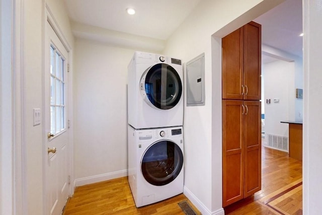 washroom with stacked washer / drying machine, light wood-type flooring, cabinet space, baseboards, and recessed lighting