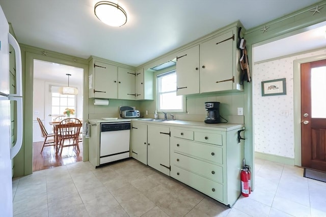 kitchen with white appliances, light countertops, a sink, wallpapered walls, and cream cabinets