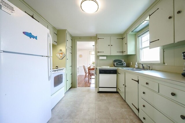 kitchen with white appliances, a sink, light countertops, and light tile patterned floors