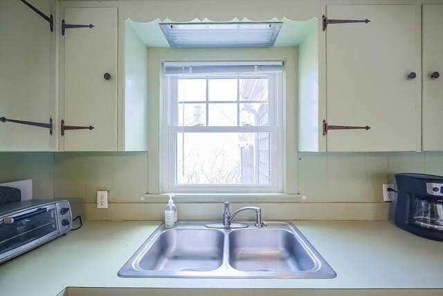 kitchen featuring a sink, white cabinetry, and light countertops