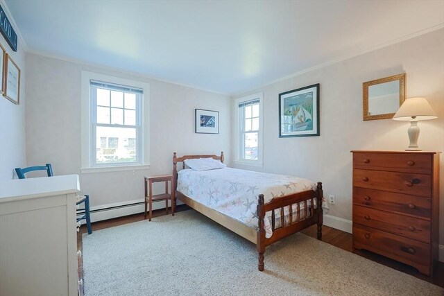 bedroom featuring a baseboard radiator, wood finished floors, ornamental molding, and baseboards