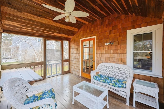 sunroom / solarium featuring lofted ceiling, wooden ceiling, a ceiling fan, plenty of natural light, and hardwood / wood-style flooring