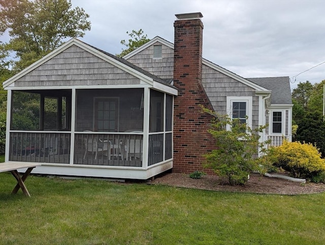 rear view of property with a sunroom, a yard, and a chimney