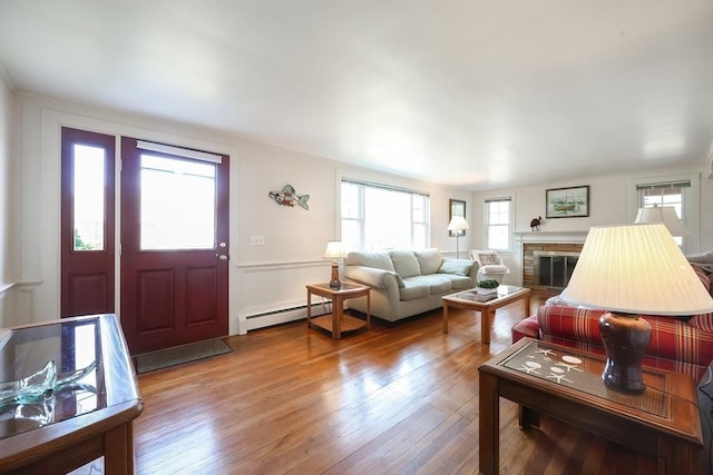 living room with baseboard heating, hardwood / wood-style floors, and a fireplace