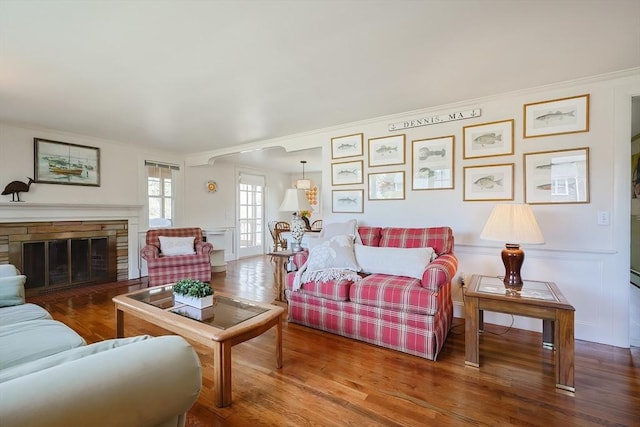 living area featuring crown molding, wood finished floors, and a stone fireplace