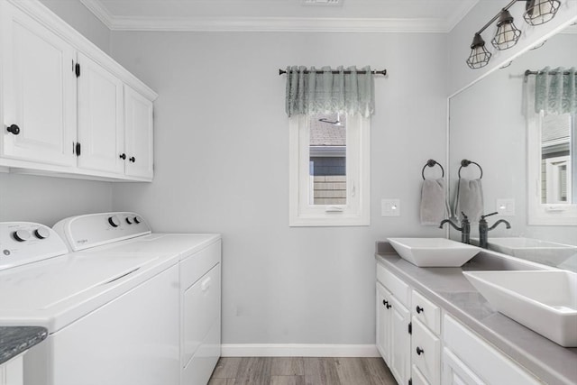 washroom featuring crown molding, light wood-style flooring, separate washer and dryer, cabinet space, and a sink