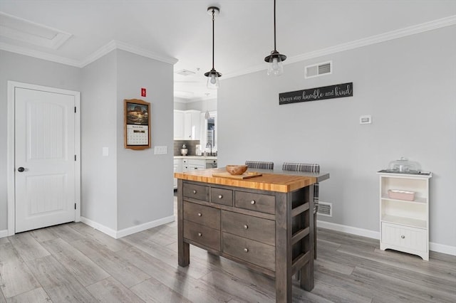 kitchen featuring visible vents, ornamental molding, a sink, light wood finished floors, and wooden counters