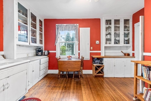 86 Glencoe St Unit 86, Boston, MA 02135 - kitchen with hardwood / wood-style flooring, white cabinetry, glass insert cabinets, light countertops, and baseboards