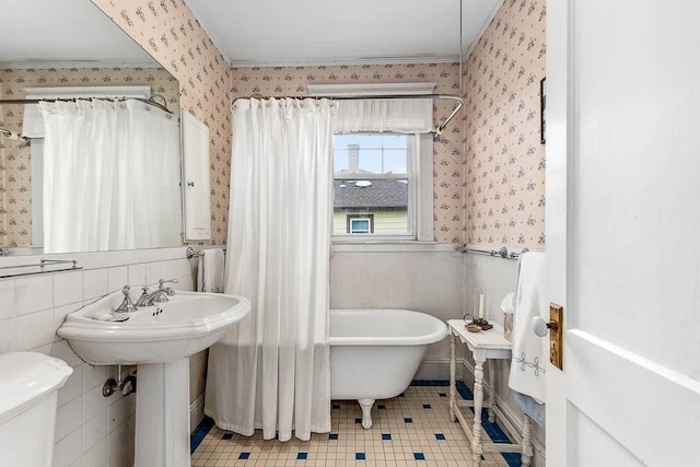 86 Glencoe St Unit 86, Boston, MA 02135 - bathroom with wallpapered walls, a freestanding tub, toilet, tile patterned flooring, and ornamental molding