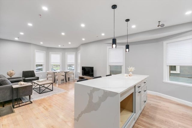 755 Boylston St Unit 1, Brookline, MA 02467 - kitchen with open floor plan, light wood-style flooring, a center island, hanging light fixtures, and light stone countertops