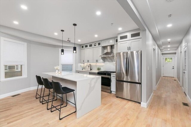 755 Boylston St Unit 1, Brookline, MA 02467 - kitchen featuring stainless steel appliances, wall chimney exhaust hood, baseboards, a center island, and a breakfast bar