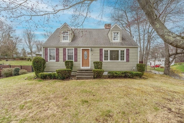cape cod house featuring roof with shingles, a chimney, fence, entry steps, and a front yard