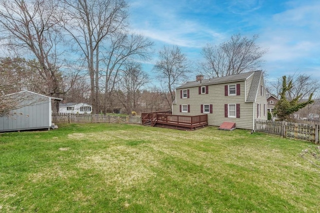 view of yard with a fenced backyard, an outbuilding, a storage shed, and a deck